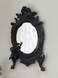 Antique cast iron oval mirror with cherub and ribbon motifs