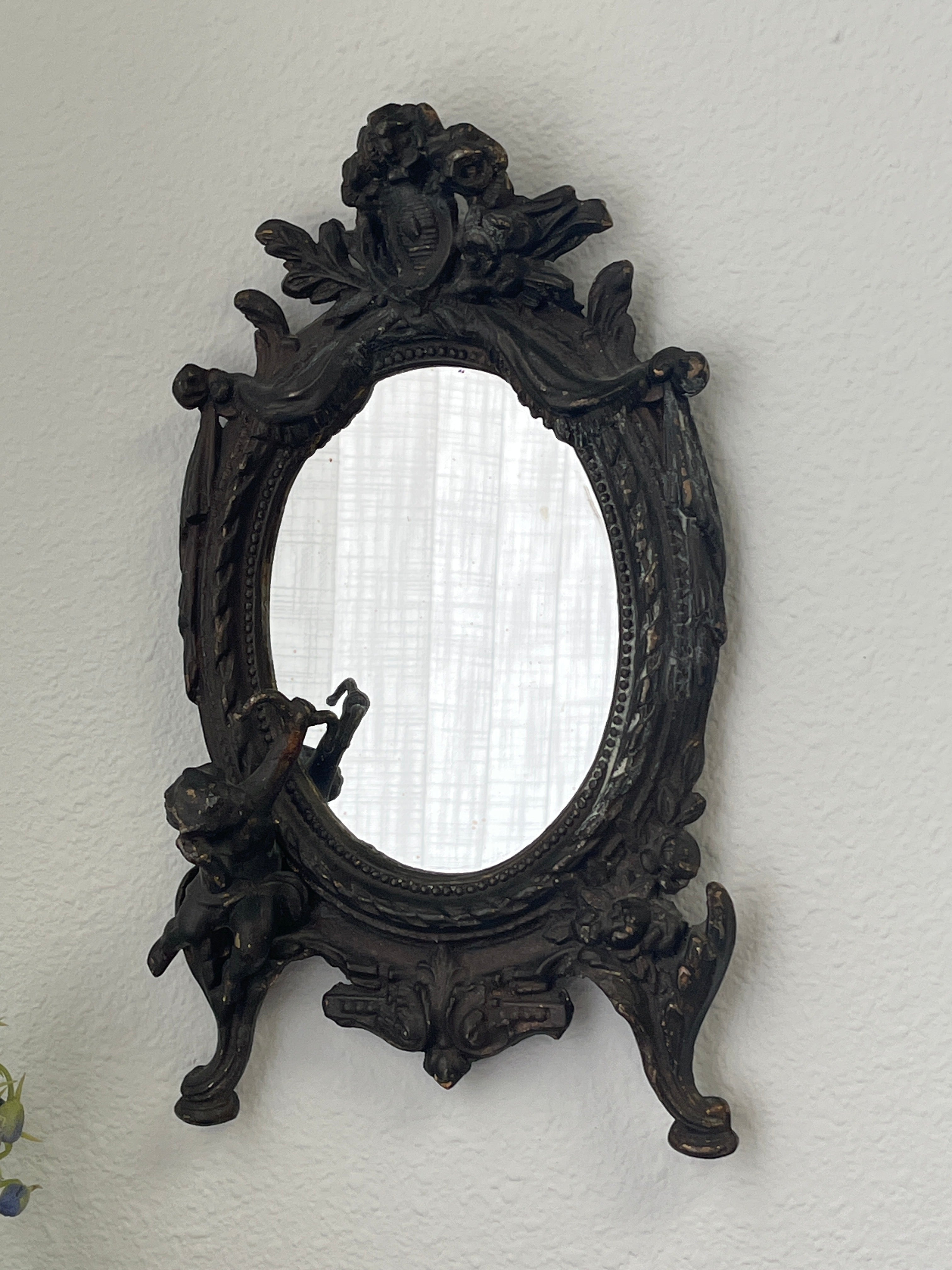 Antique cast iron oval mirror with cherub and ribbon motifs